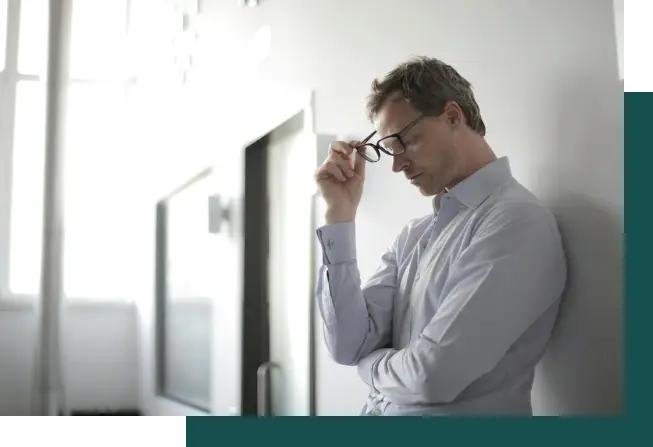 man with glasses holding holding head with his hands